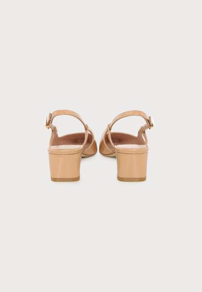 Paire de sandales à talons blocs beige avec brides à la cheville et petites boucles dorées, vues de dos sur fond blanc.