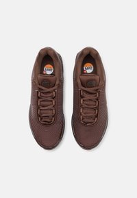 Paire de baskets Nike Air Max marron vues de dessus sur un fond gris clair.