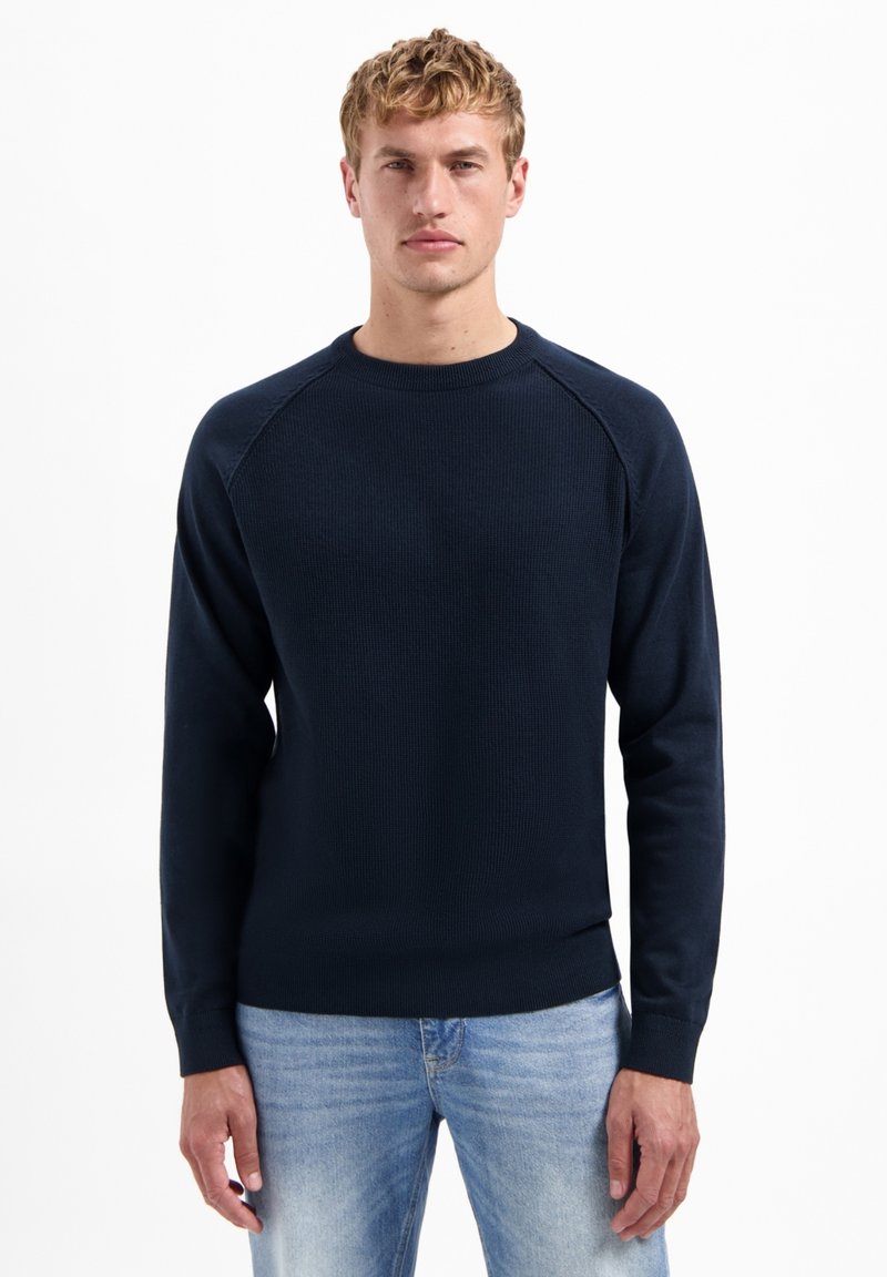 Navyblauwe gebreide sweatshirt met ronde hals, ribgebreide manchetten en zoom. Heeft een textuurstof en raglanmouwen voor een ontspannen pasvorm.