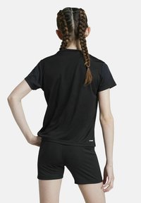 Schwarzes Sporthemd mit Rundhalsausschnitt, kombiniert mit passender Shorts. Der Stoff wirkt glatt und leicht, ideal für Sportbekleidung.
