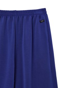 Pantaloni sportivi viola con elastico in vita, tasche laterali e una piccola etichetta nera sul lato sinistro. Tessuto morbido e leggero.