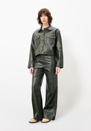 Groene neplederen cropped jacket met grote voorzakken, gecombineerd met wijde broek in hetzelfde materiaal, met een textuurafwerking.
