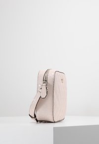 Borsa a tracolla rosa trapuntata con una texture liscia, dotata di chiusura a zip e una tracolla regolabile. Accenti in metallo argentato visibili.