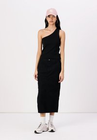 Black, one-shoulder ribbed top paired with a long black skirt featuring a pocket. Accessories include a light pink cap and sneakers.