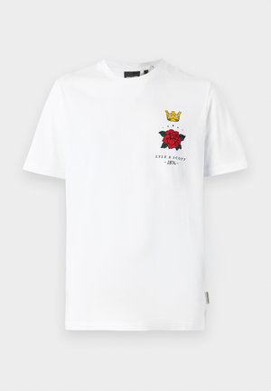 T-shirt en coton blanc présentant un design de rose rouge, du texte noir et un graphique de couronne jaune sur la poitrine à gauche. Manches courtes, col rond.