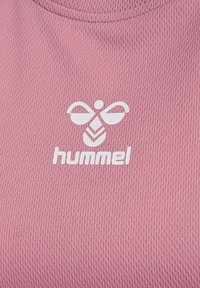 Roze sportshirt met een textuurrijke stof, een ronde hals en een wit logo met de tekst "hummel" aan de onderkant.