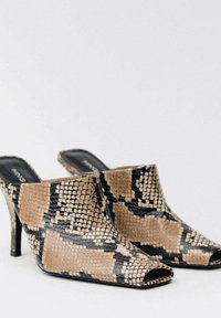 Mules ouvertes en imprimé serpent beige et noir, avec une finition lisse et un talon haut slim.
