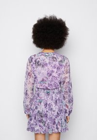 Vestídio floral em tons de roxo com mangas longas transparentes, cintura franzida e saia em camadas. Apresenta um padrão misto de rosas.