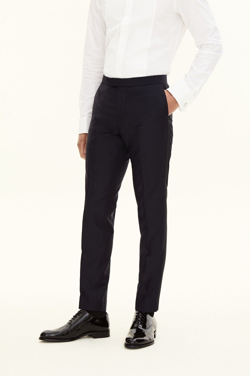Granatowe spodnie garniturowe o dopasowanym kroju, z płaskim przodem i bocznymi kieszeniami, zestawione z wypolerowanymi czarnymi skórzanymi butami.