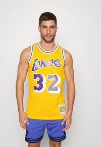 Maglietta da basket in rete gialla con accenti viola, con il testo "Lakers" e il numero "32" in bianco. Abbinata a pantaloni corti blu.