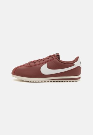 Sneaker Nike Cortez color granata con logo Swoosh bianco e suola color crema, vista di lato su sfondo uniforme.