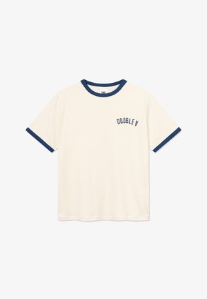 Kremas medvilninis marškinėlis su tamsiai mėlynu ribotu apykakle ir rankovių manžetėmis. Kairėje krūtinės pusėje yra užrašas „DOUBLE V“. Trumpomis rankovėmis, laisvo kirpimo.