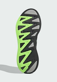 Sole topánky s čiernym základom a cik-cak vzorom v jasne zelenej a šedej akcentoch, navrhnutá pre trakciu a flexibilitu.