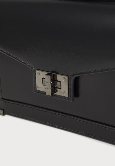Black leather bag with a smooth texture, featuring a metallic clasp and neat stitching along the edges. Compact rectangular shape.