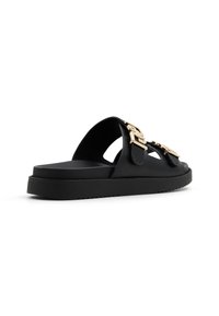 Black leather slide sandals feature gold-tone buckles, a flat platform sole, and cut-out design details for ventilation. Textured sole for grip.