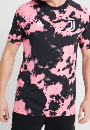 Mand iført pink og sort tie-dye Juventus fodboldtrøje med Adidas-logo på brystet, kombineret med sorte shorts.