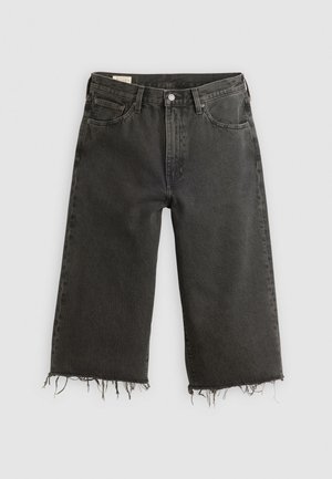 Czarne dżinsowe spodnie typu wide-leg z surowym wykończeniem, z pięcioma kieszeniami i zapięciem na metalowy guzik. Tekstura jest nieco chropowata.