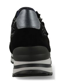 Zwarte suède schoen met zilveren textielaccenten, voorzien van een gevoerde hak en een wit-zwart gestreepte zool. Achteraan is de ritsdetail te zien.