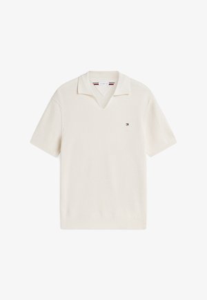 Κοντομάνικο πλεκτό πόλο σε κρεμ απόχρωση με ραβδωτή υφή, ανοιχτό γιακά και μικρό ορθογώνιο λογότυπο στο αριστερό μέρος του στήθους.