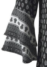 Schwarz-weißer gemusterter Stoff mit Rüschensäumen, intricaten floralen und geometrischen Designs, glatter Textur und geschichteter Optik.