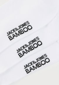 Chaussettes blanches en bambou avec texte noir : "JACK & JONES" et "BAMBOO." Texture lisse avec une forme de chaussette classique. Design uni sans motifs.