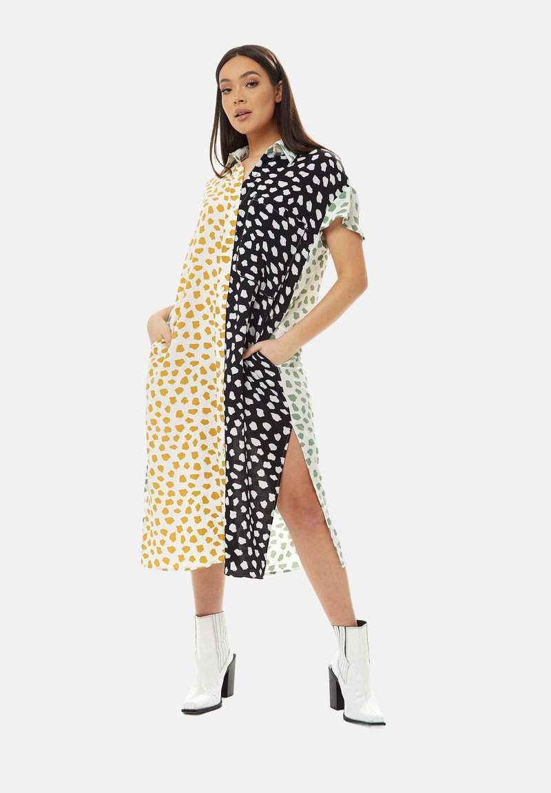 Collared dress with four color blocks: yellow, black, mint green, and white. Dotted pattern, short sleeves, side slits, and pockets.