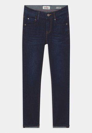 Jean skinny bleu foncé avec poches avant, fermeture par bouton et surpiqûres orange visibles sur un fond clair.