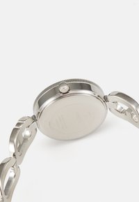 Orologio in acciaio inossidabile con cassa liscia e lucidata e bracciale integrato. Presenta una corona prominente e dettagli incisi sul retro.