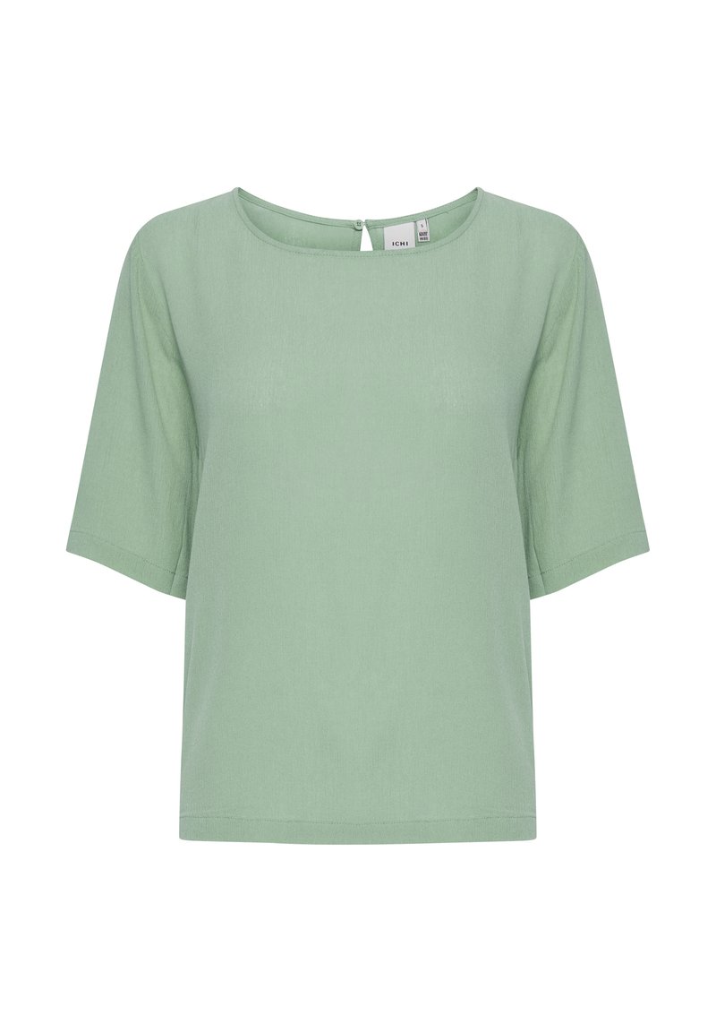 Voľný krátky rukáv top v svetlozelené farbe, s okrúhlym výstrihom a detailom v tvare kľúča na zadnej strane. Vyrobené z hladkej, jemnej tkaniny.