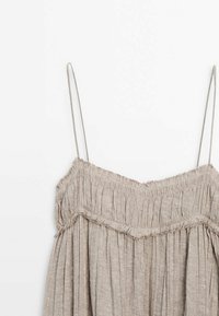 Haut sans bretelles en lin beige avec une texture froncée, présentant un détail de bord effiloché et de fines bretelles réglables.