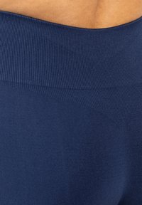 Marina leggings med ribbat midjeband och slät textur. Tyget är elastiskt och kroppsnära, vilket ger komfort och stöd.