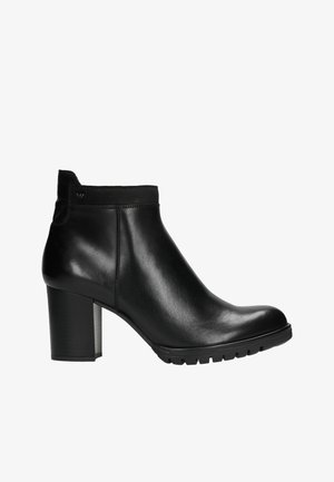 Černá kožená kotníková bota s hladkým povrchem, robustním podpatkem a gumovou podrážkou. Disponuje těsným elastickým vrškem a minimálními švy.