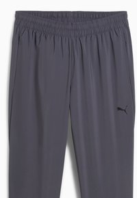 Γκρι αθλητικό παντελόνι με ελαστική μέση, δύο πλαϊνές τσέπες και ένα μικρό μαύρο λογότυπο στο κάτω μέρος του αριστερού ποδιού. Λείο, ελαφρύ ύφασμα.