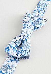 Pajarita floral hecha de tela que presenta un patrón floral en azul y blanco, con varios tonos de azul y algunos acentos en azul oscuro.