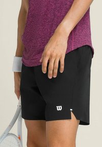 Schwarze Sportshorts mit einem weißen Logo unten rechts, seitlichen Schlitzen für Bewegungsfreiheit und einem glatten, leichten Stoff.