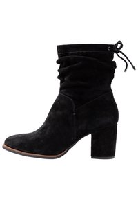 Stivaletto in suede nero con design morbido, punta rotonda e tacco a blocco. Presenta un dettaglio con cordoncino nella parte superiore per regolare la vestibilità.