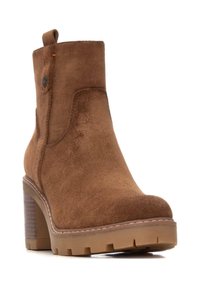 Bota de tobillo de ante marrón con un tacón grueso, superficie texturizada, costuras en el panel lateral y un pequeño lazo en la parte posterior para facilitar su uso.