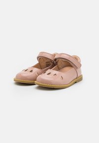 Zapatos de charol rosa con diseños recortados, correa ajustable, punta redondeada y suela de goma amarilla. Diseño compacto y ligero.