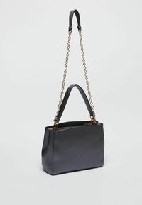 Borsa a mano in pelle nera con una texture liscia, dotata di tracolla a catena e doppio manico. Chiusura con zip in alto.