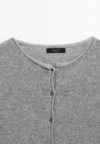 Gray knit cardigan with a rounded neckline, featuring a front button closure and a soft texture. Black tag visible at the neck.