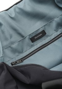 Čierny bag s vnútrom v svetlomodrej farbe. Má hladkú textúru, etiketu s nápisom "Matinique" a zipsový oddiel.