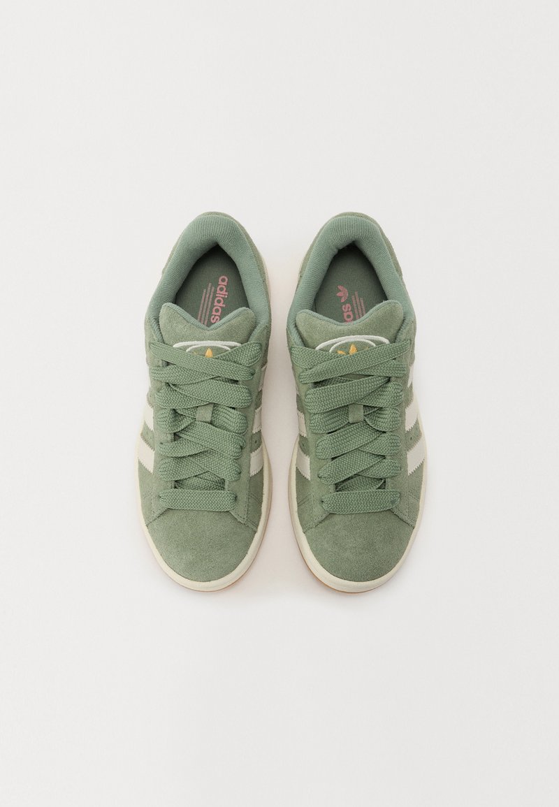 Zapatillas de ante verde con rayas blancas y cordones texturizados. Cuentan con una lengüeta y plantilla acolchadas, diseñadas para un uso casual.
