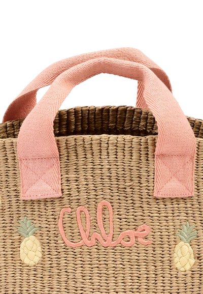 Torba na ramię wykonana z plecionej słomy z różowymi tkaninowymi uchwytami, haftowanym imieniem "Chloé" i małymi wzorami ananasa po obu stronach.