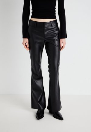 Zwarte neplederen flared pants met een gladde textuur. Bevat voorzakken en een aansluitende tailleband. Gepaard met zwarte puntige schoenen.