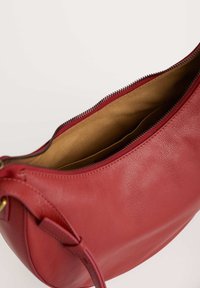 Borsa a mano rossa in pelle con finitura texturizzata, dotata di chiusura a zip, fodera interna beige e un manico liscio.
