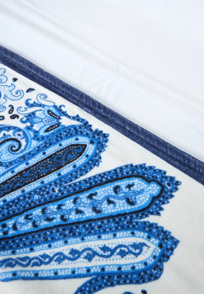 Tissu blanc avec un motif cachemire bleu détaillé et une bordure bleu foncé sur le bord.