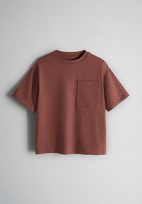 Barna rövid ujjú póló kerek nyakkivágással és egyetlen mellkasi zsebbel, egyszínű világosszürke háttér előtt bemutatva.