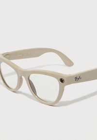 Beige acetatsolbriller med firkantet stel, der har transparente linser og et sort Ray-Ban-logo på stanget.