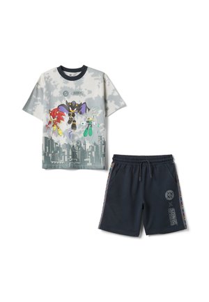 T-shirt tie-dye bianca e grigia a tema Sonic con personaggi e stampa paesaggio urbano, abbinata a pantaloncini neri con coulisse con loghi Sonic e righe laterali.
