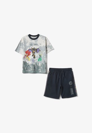 Tie-Dye T-Shirt in Weiß und Grau mit Sonic-Motiv, bedruckt mit Charakteren und Stadtsilhouette, kombiniert mit schwarzen Shorts mit Kordelzug, Sonic-Logos und seitlichen Streifen.